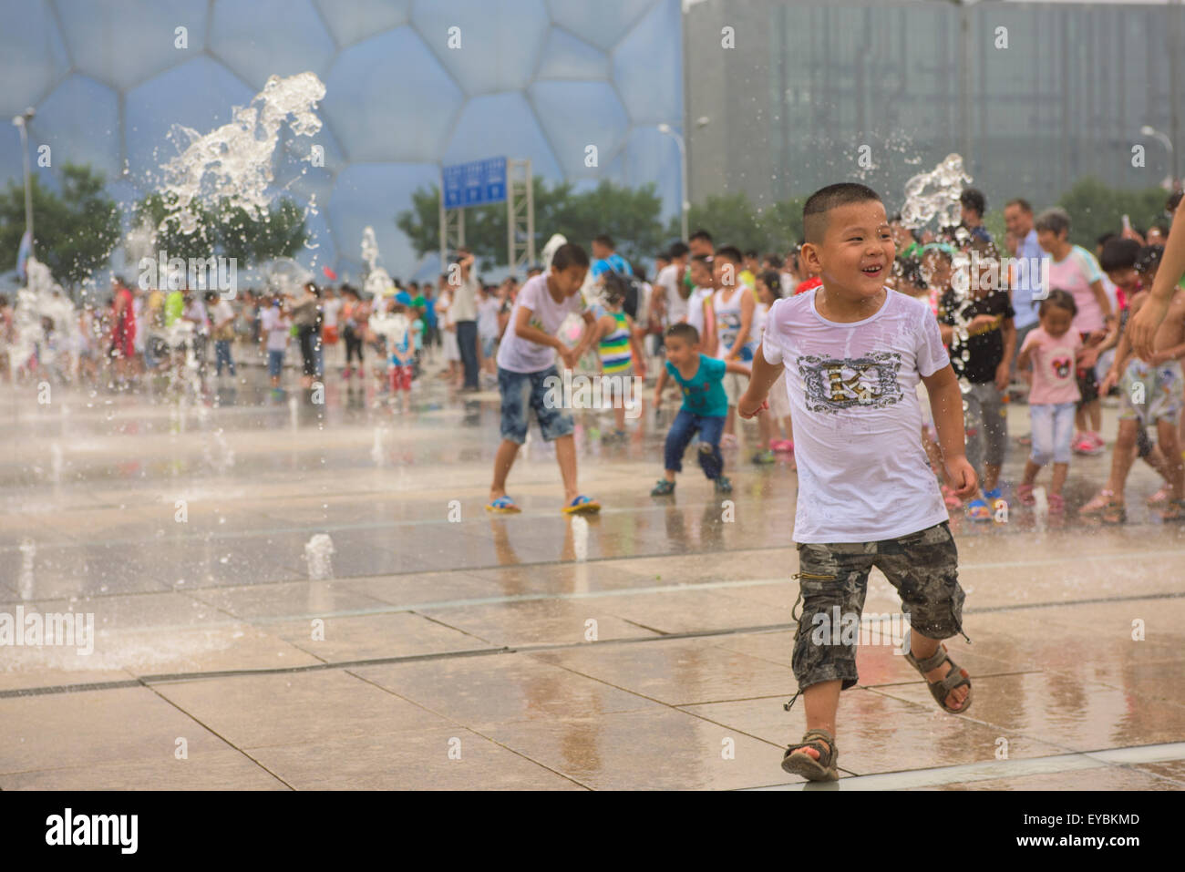 I bambini cinesi divertendosi tra l'acqua-sprinkler a Pechino la Olympic Park - Luglio 2015 Foto Stock