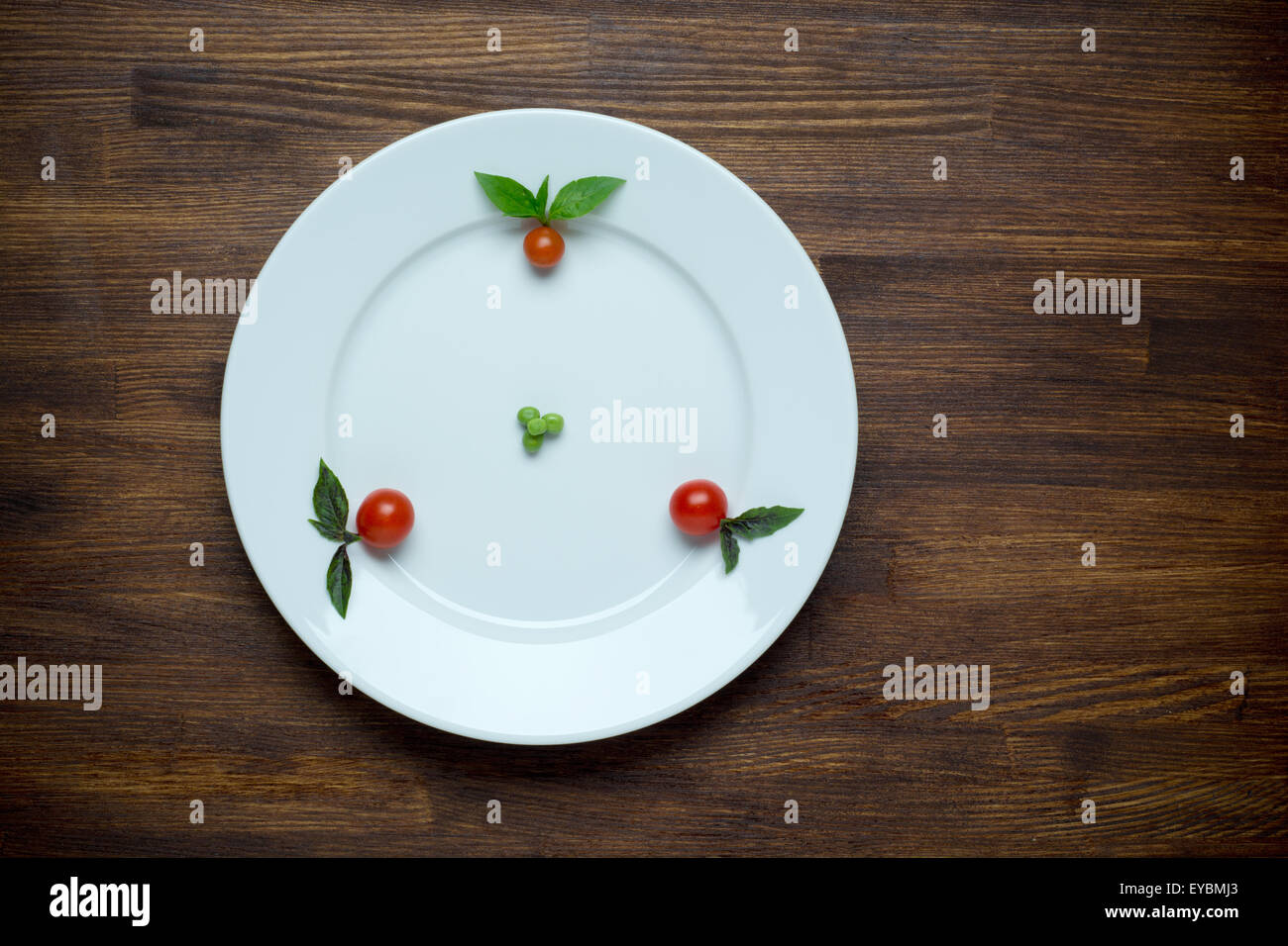 Cibo sano tema: piselli verdi su una piastra con pomodori ciliegia. Tavolo in legno sfondo Foto Stock