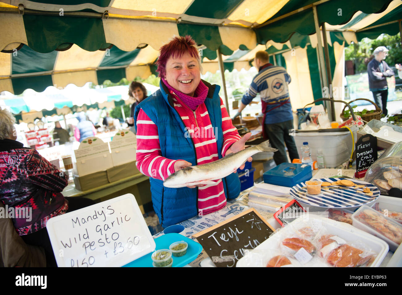 Una donna vendita stallholder fresco pescato localmente la spigola al St Dogmaels mercato alimentare, West Wales UK Foto Stock