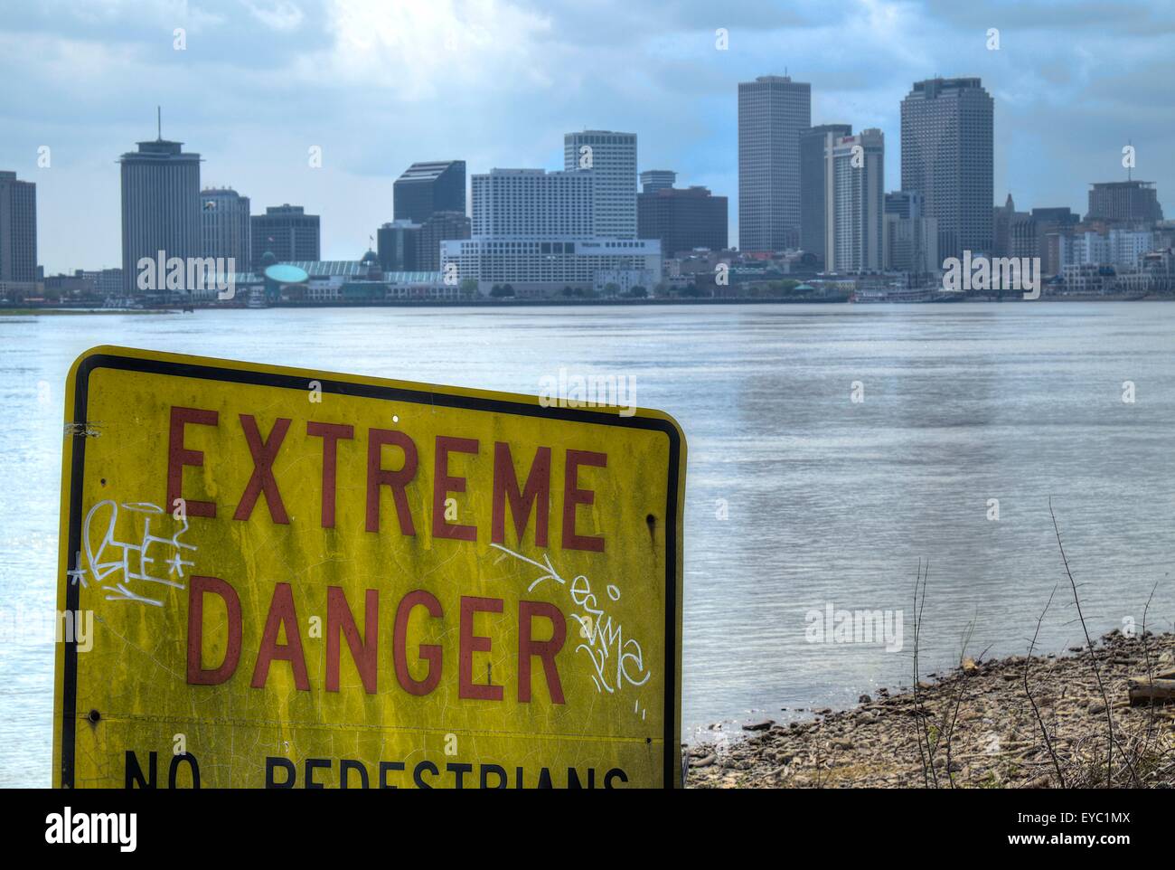 Un cartello che recita "estremo pericolo' con lo skyline di New Orleans in background. Preso da Crescent parco nei pressi del fiume Mississippi. Foto Stock