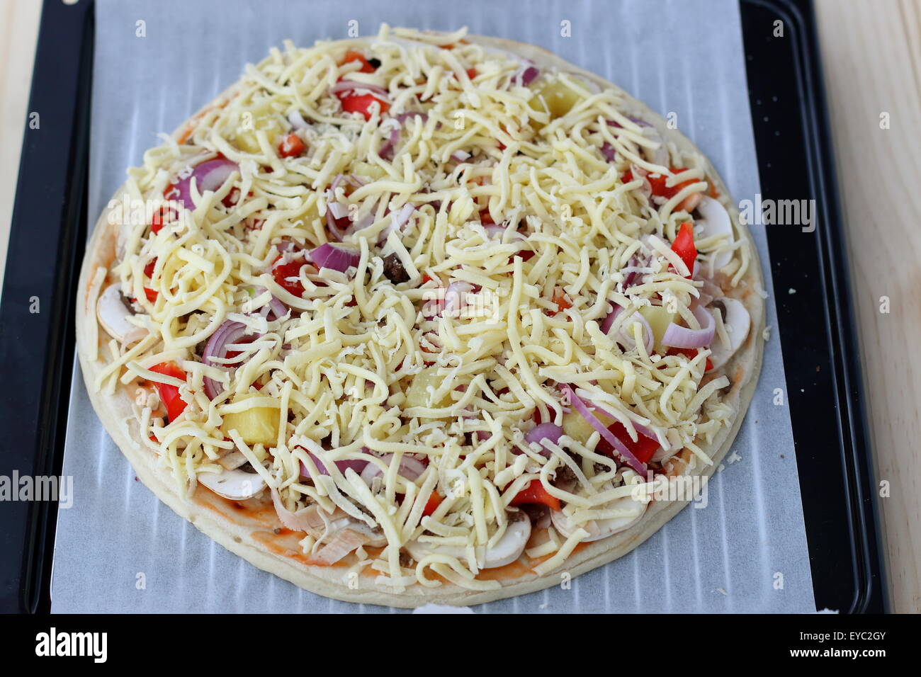 In casa la pizza cruda su un foglio di carta forno Foto stock - Alamy