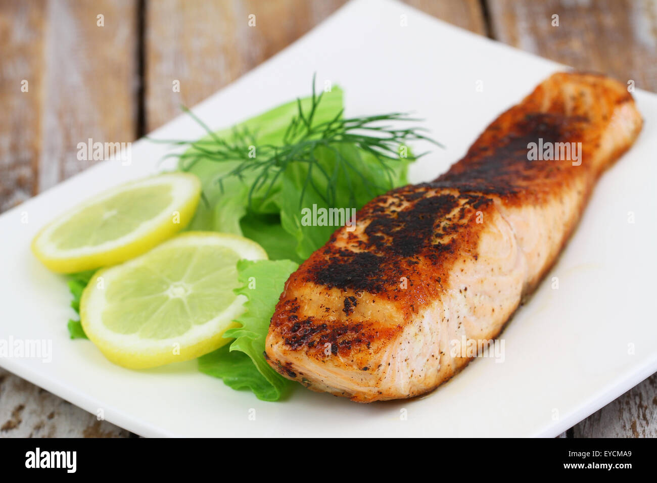 Salmone alla griglia con insalata di contorno e limone, primo piano Foto Stock