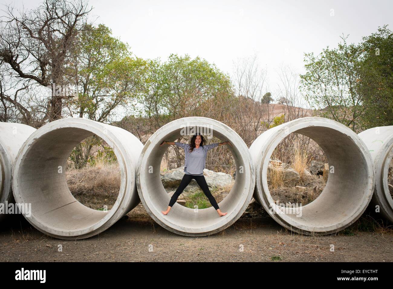Ritratto di giovane donna in piedi all'interno del tubo di calcestruzzo nel paesaggio rurale Foto Stock
