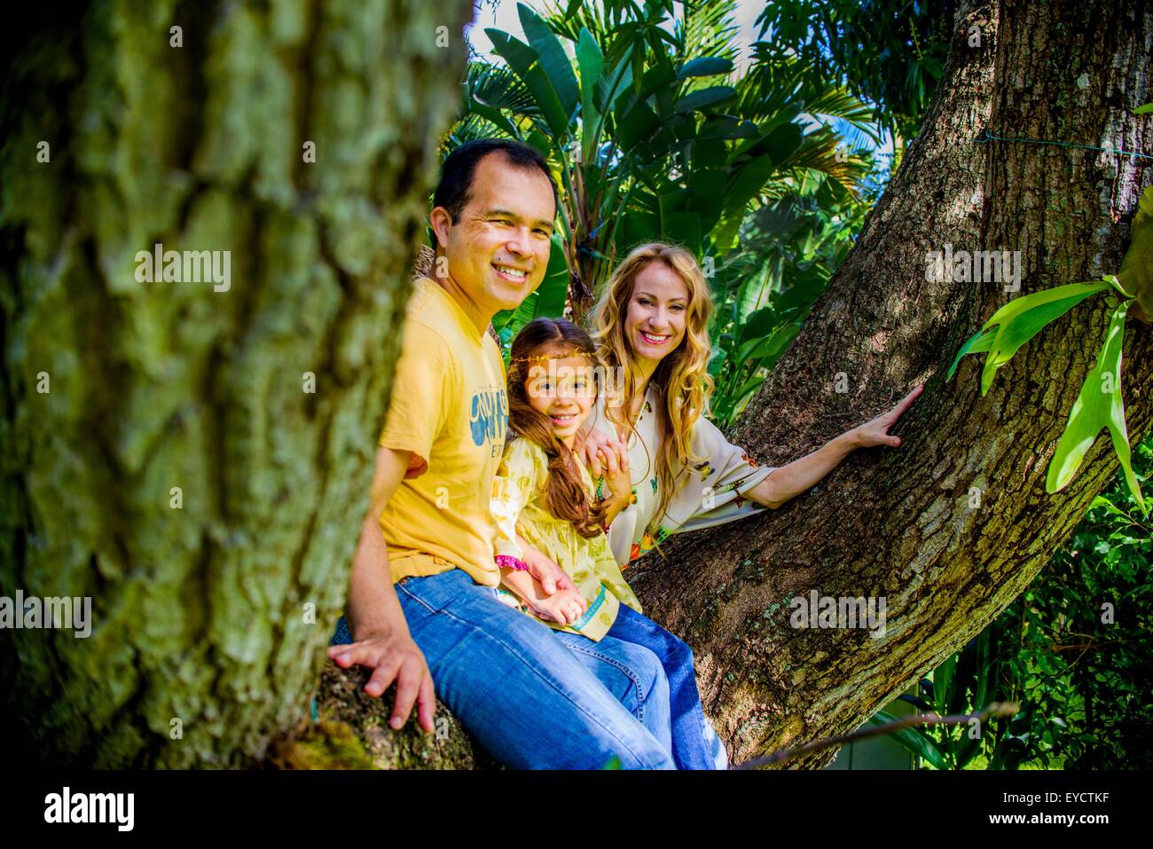 Ritratto di Coppia matura e figlia seduti sul giardino ramo di albero Foto Stock