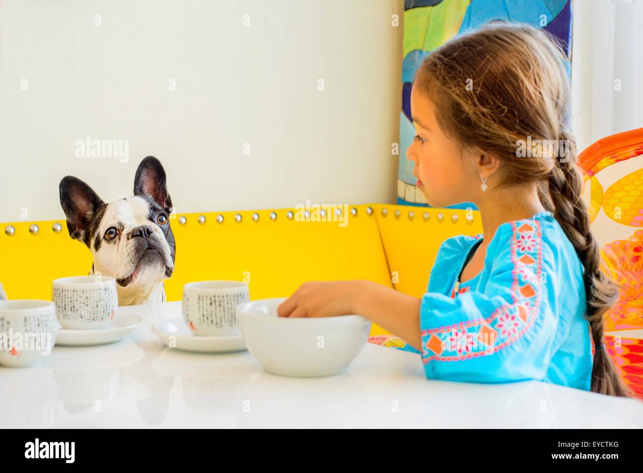 Ragazza e cane guardando ogni altro a tavola Foto Stock
