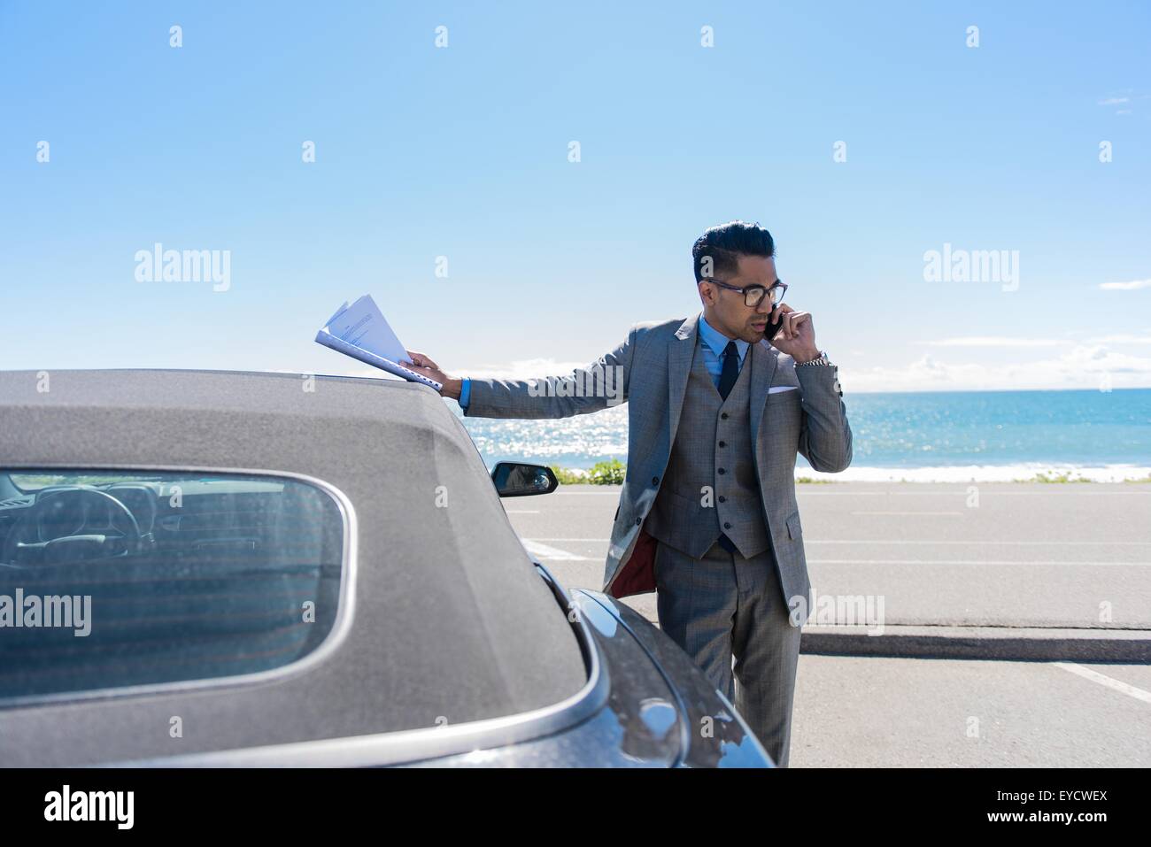 Giovane imprenditore a coastal parcheggio parlando sullo smartphone Foto Stock