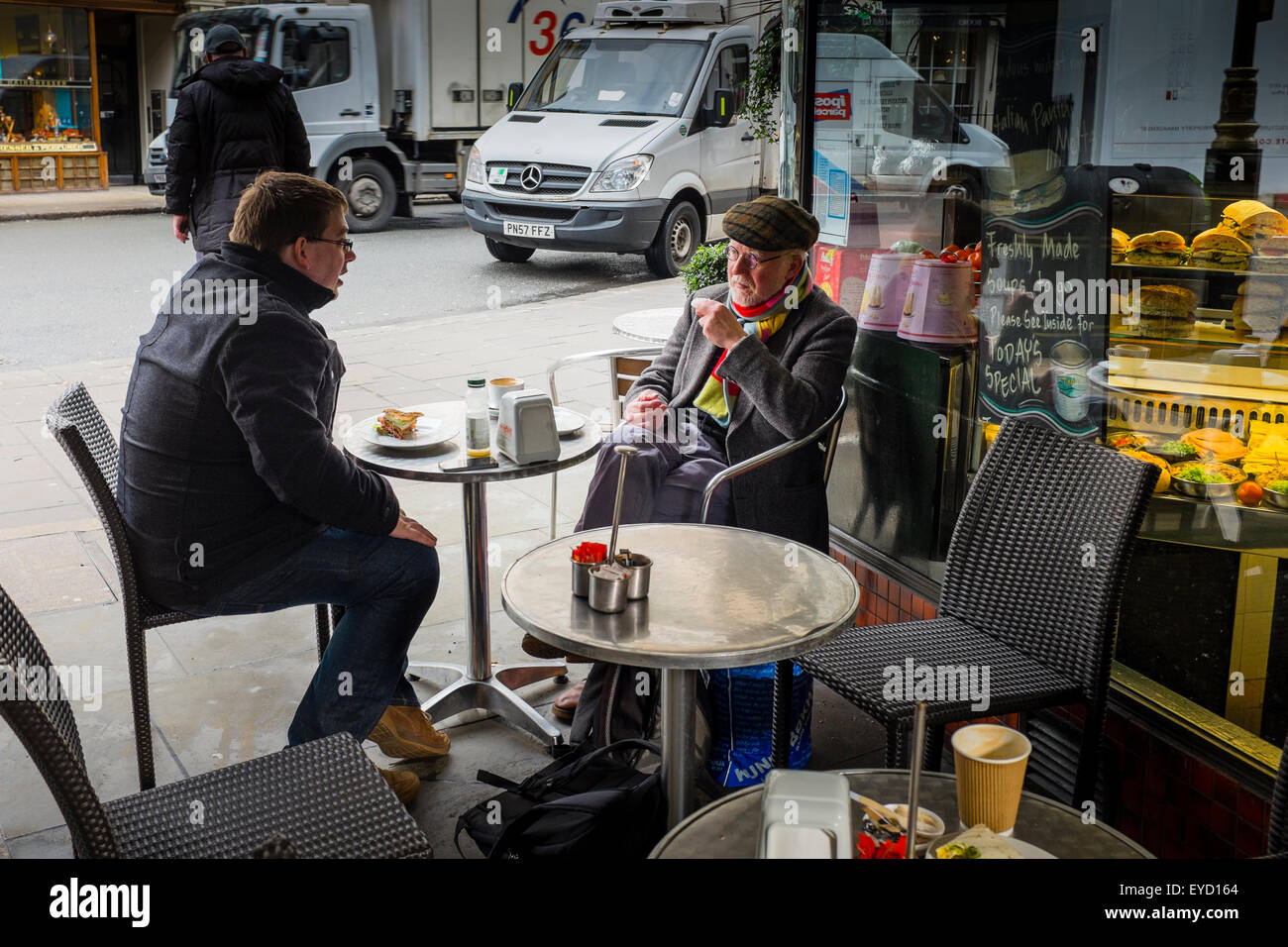 Due uomini avente una conversazione in un cafe' sul marciapiede, London, Regno Unito Foto Stock