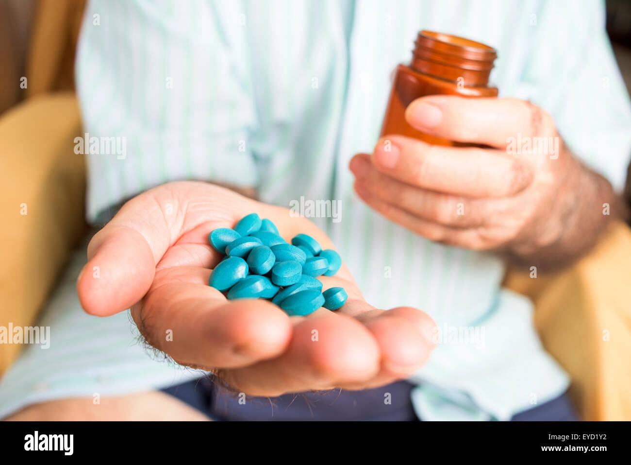 Primo piano di un vecchio uomo caucasico con un mucchio di blu pillole in mano Foto Stock