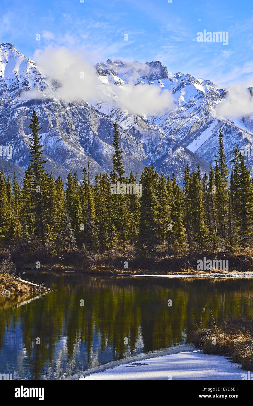 Un paesaggio verticale immagine della Miette mountain range da un open water pond e nuvole bianche, Foto Stock