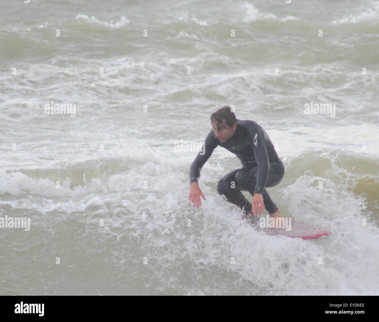 Shoreham, East Sussex, Regno Unito. 27 Luglio 2015. Surfer ottiene un'onda fuori da Southwick Beach Foto Stock