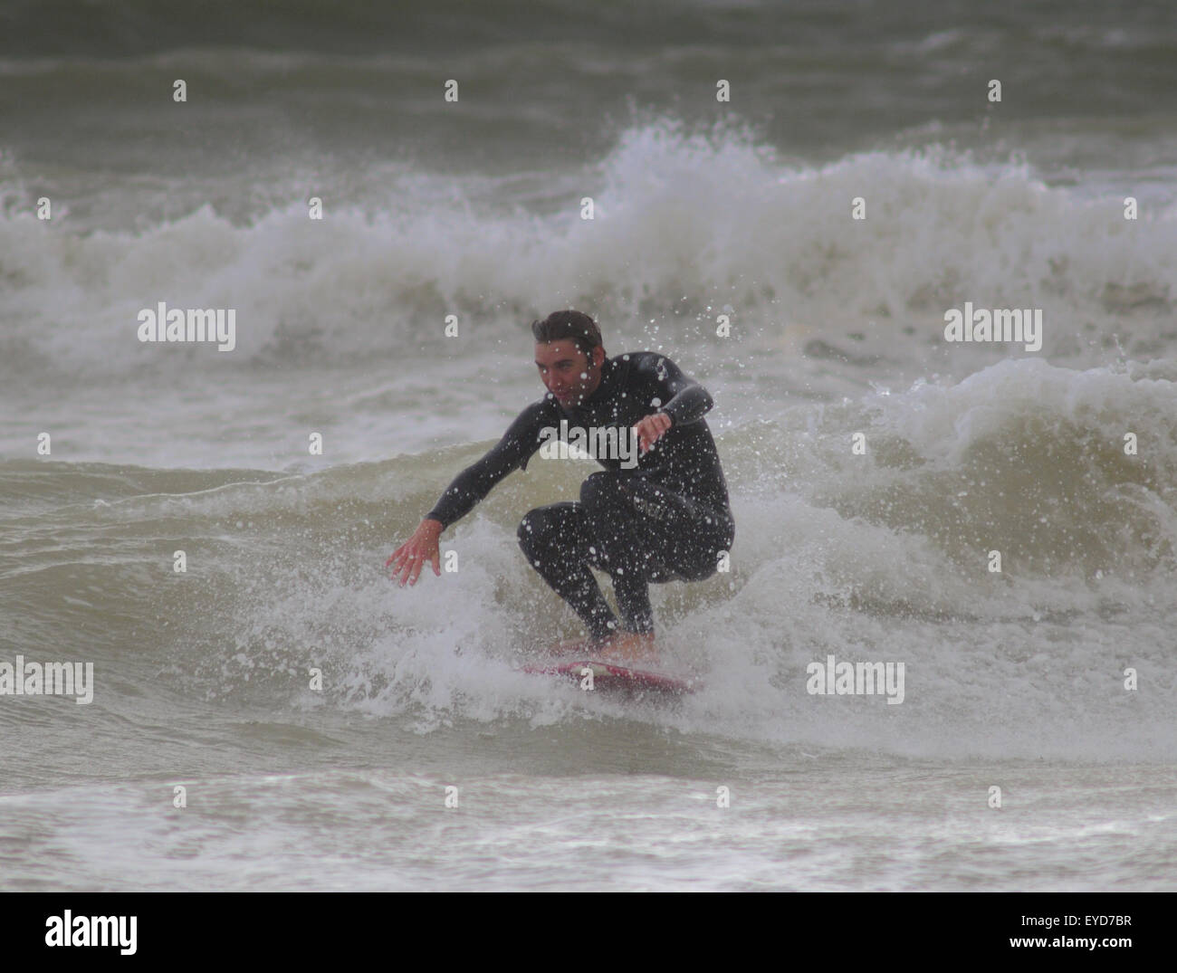 Shoreham, East Sussex, Regno Unito. 27 Luglio 2015. Surfer ottiene un'onda fuori da Southwick Beach Foto Stock