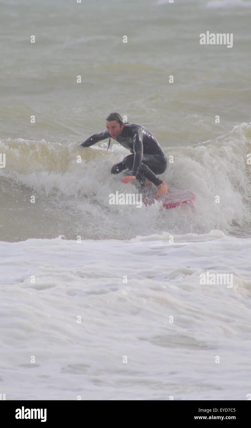 Shoreham, East Sussex, Regno Unito. 27 Luglio 2015. Surfer ottiene un'onda fuori da Southwick Beach Foto Stock