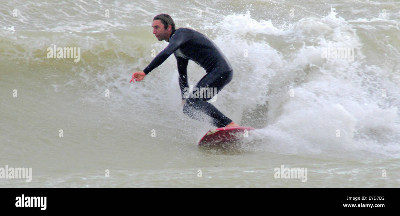Shoreham, East Sussex, Regno Unito. 27 Luglio 2015. Surfer ottiene un'onda fuori da Southwick Beach Foto Stock