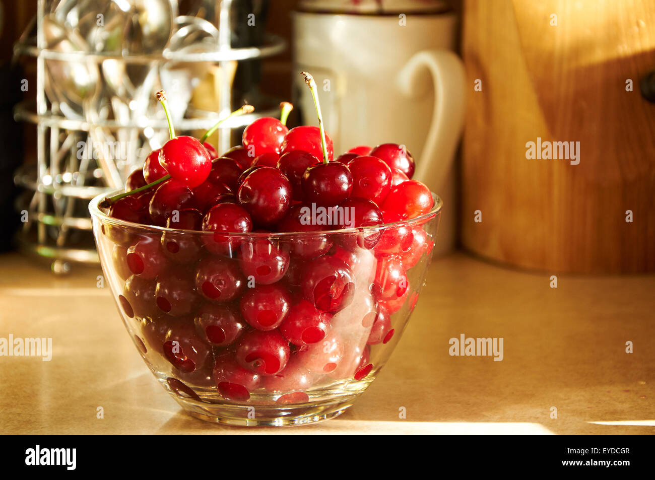 Vaso di vetro pieno di red ciliegie mature sul tavolo Foto Stock