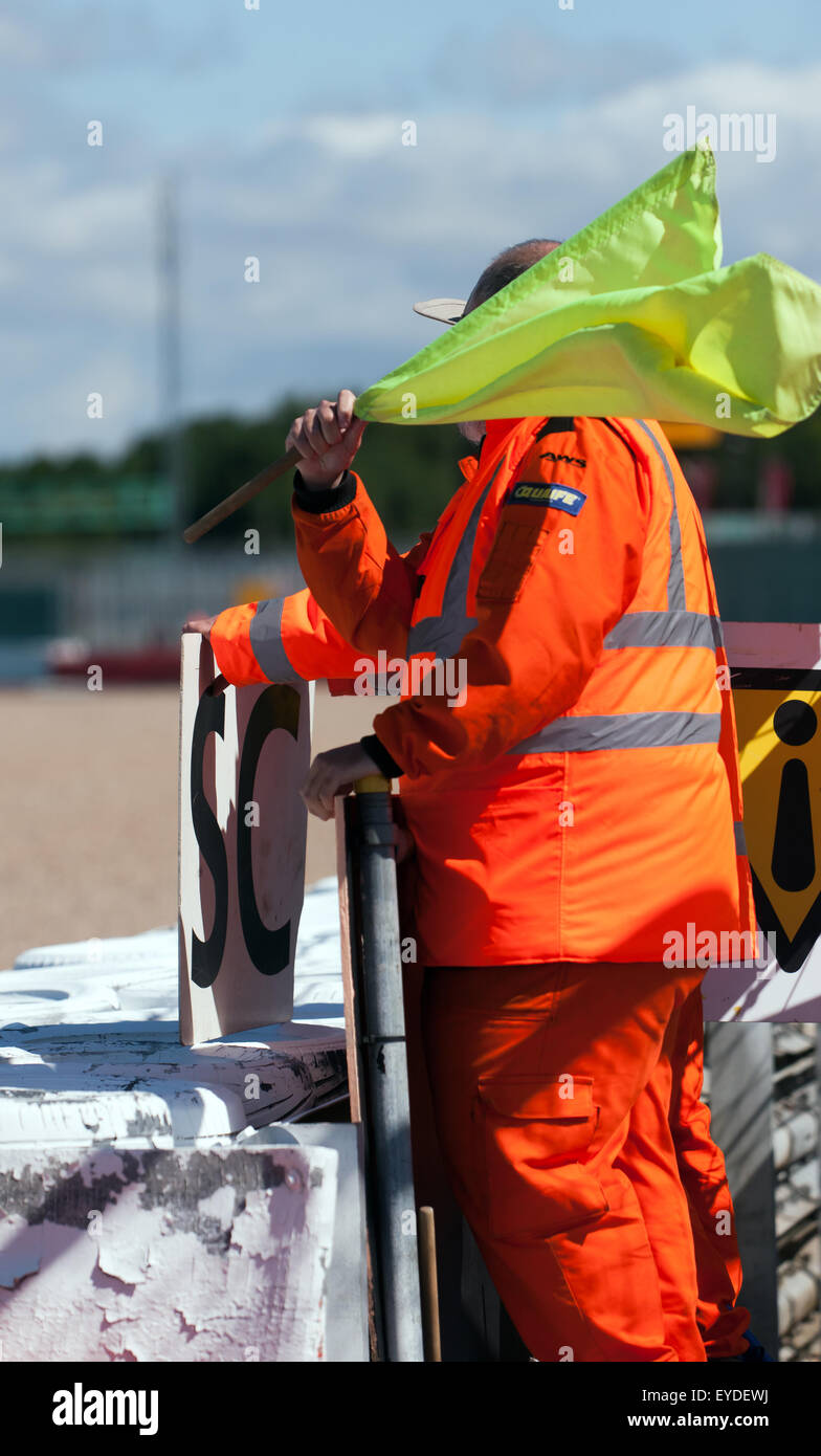 Una gara a bordo pista onde marshal un giallo di avvertimento pericolo bandiera durante una gara a Silverstone Classc. Foto Stock