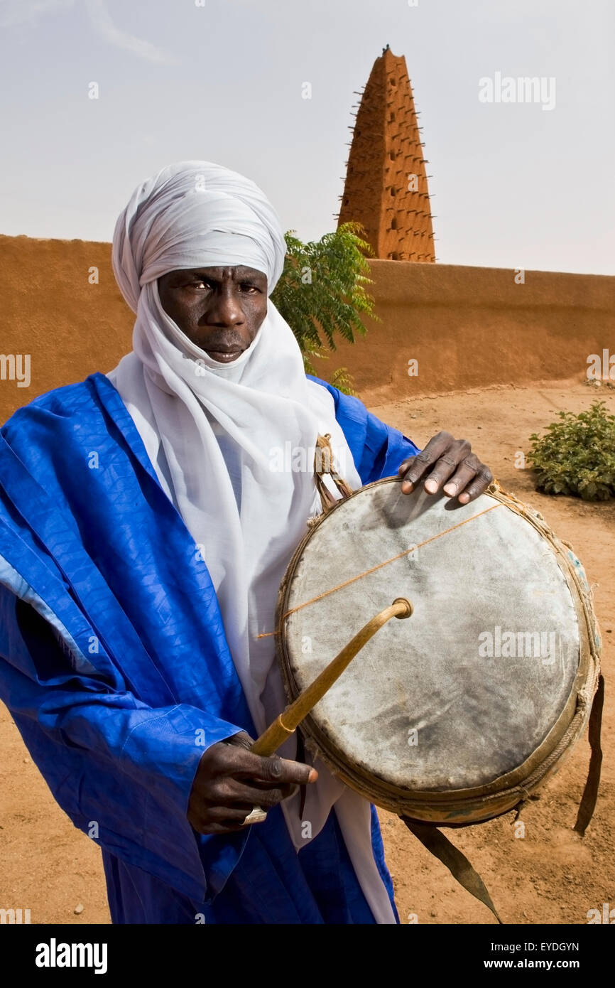 Il Niger, il Deserto del Sahara, Regione di Agadez, Tuareg il batterista in piedi accanto ad Agadez grande moschea; Agadez Foto Stock