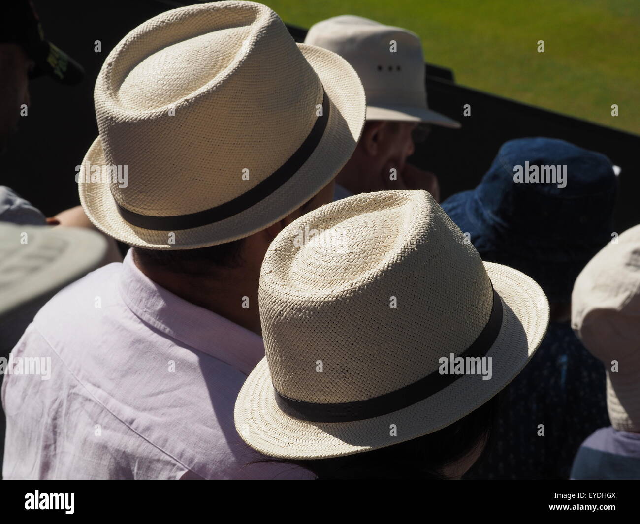 Paglia Identiical Panama cappelli nella luce del sole tra gli spettatori nelle gabbie a Wimbledon All England Tennis Londra Foto Stock