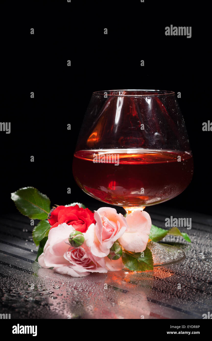 Ancora vita bicchiere di vino bevanda liquida oggetti di studio alcol rose fiore rosa natura verticale impianto close up foglie verdi Foto Stock