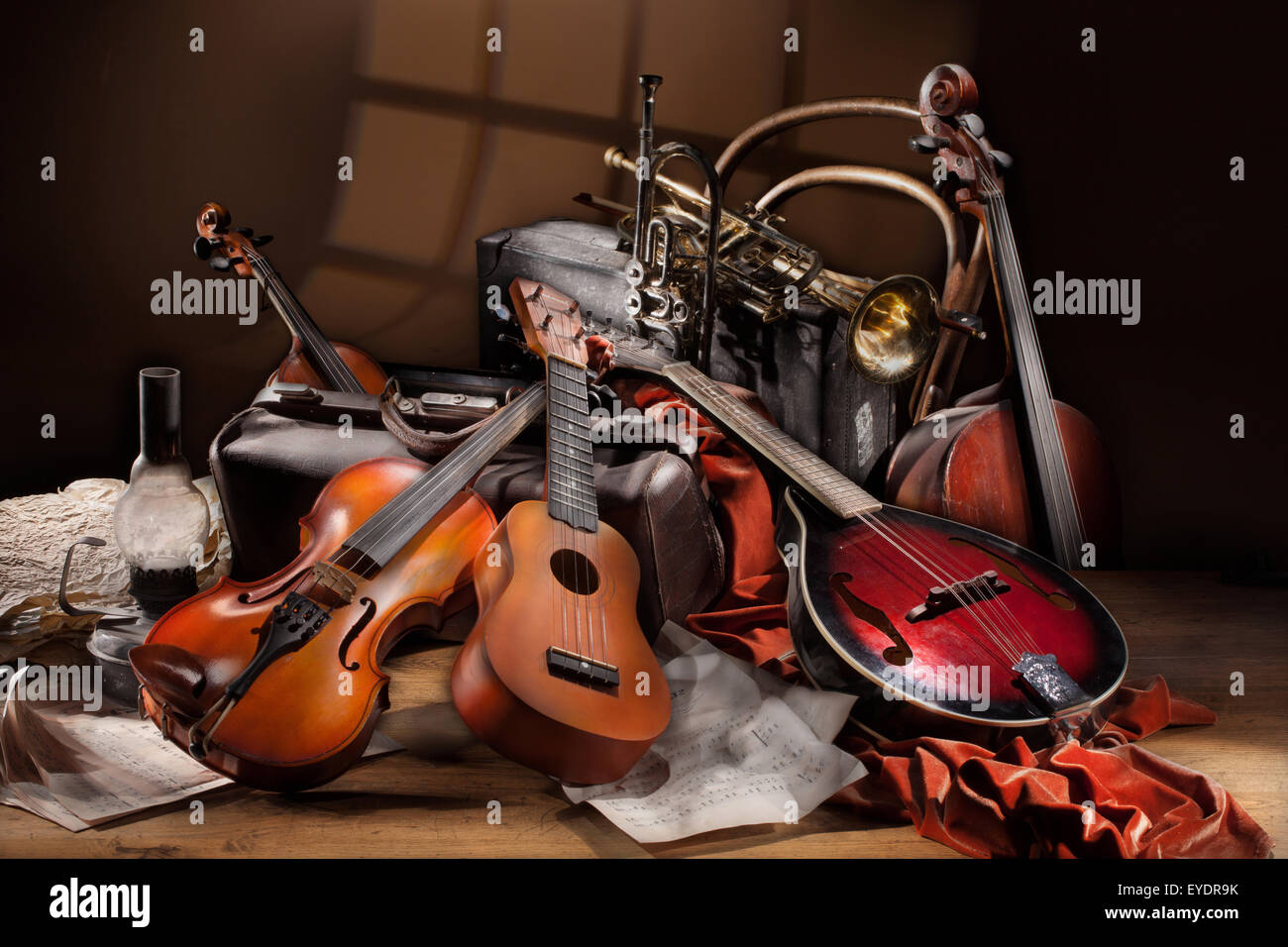 Ancora vita musicale arte musica stringa strumento folk chitarra ukulele violino tromba di metallo in ottone tavolo in legno tessuto studio Foto Stock