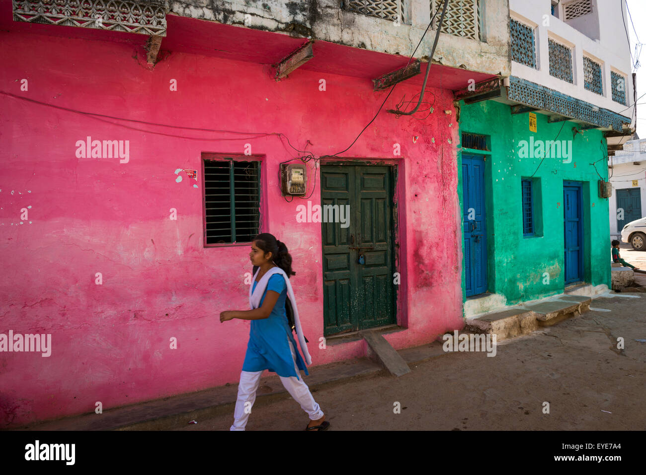 Giovane donna indiana oltrepassando case colorate nel vecchio villaggio di Khajuraho, Madhya Pradesh, India Foto Stock