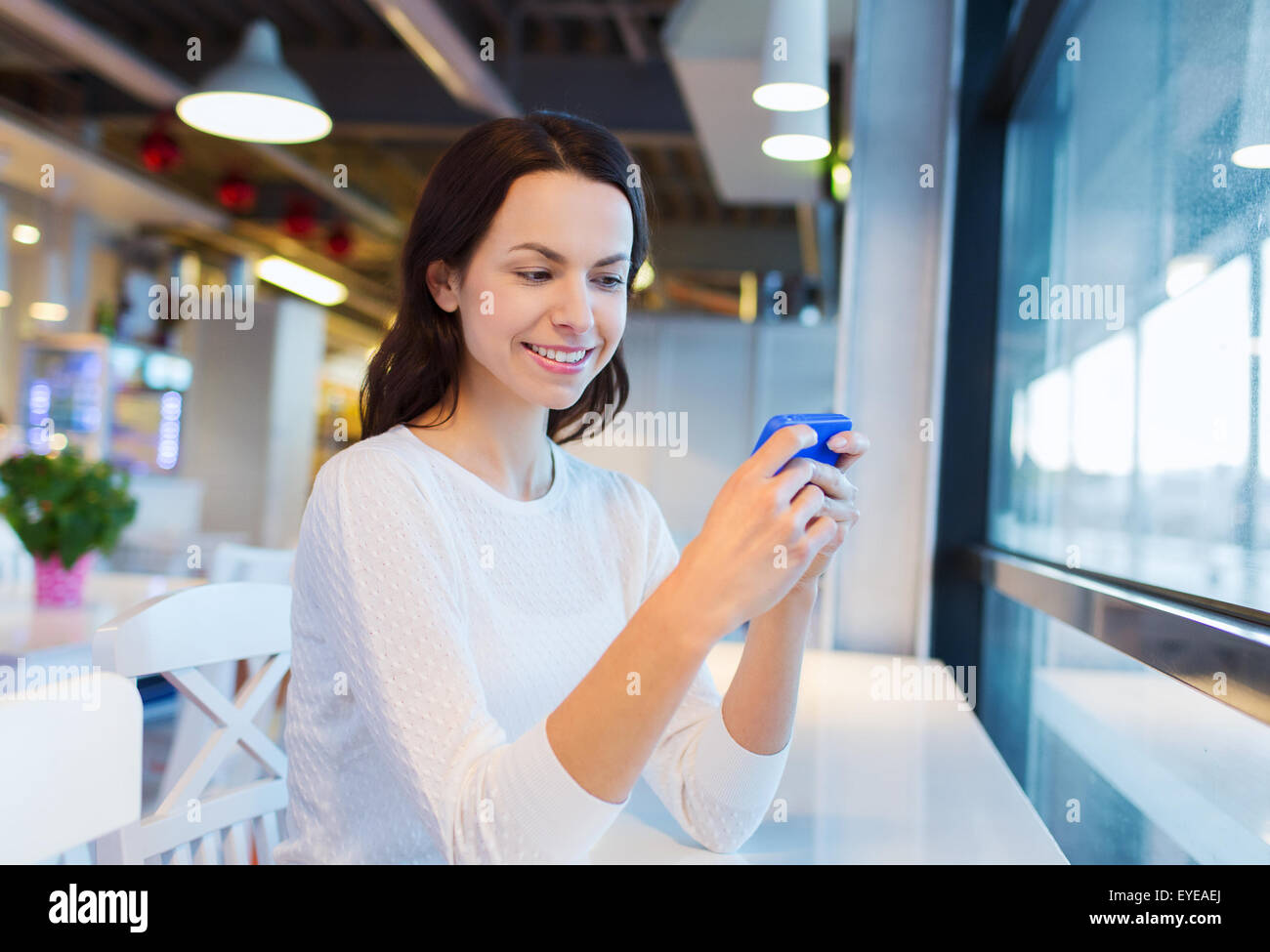 Donna sorridente con lo smartphone al cafe Foto Stock