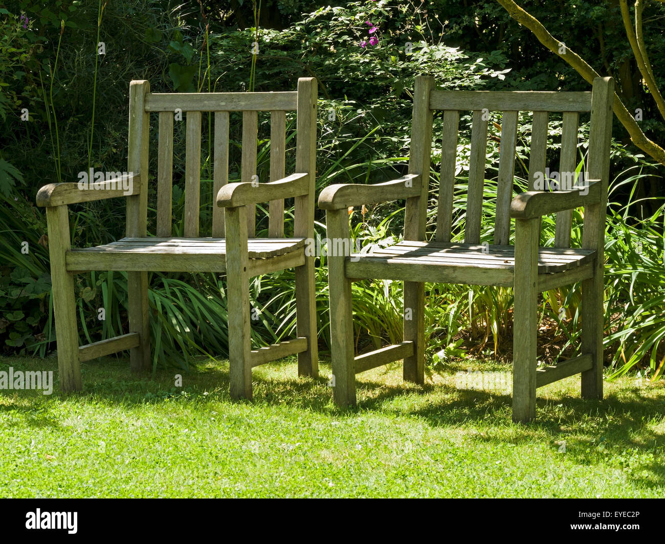 Due, soleggiato giardino in legno posti su prato, Barnsdale Gardens, Rutland, UK. Foto Stock