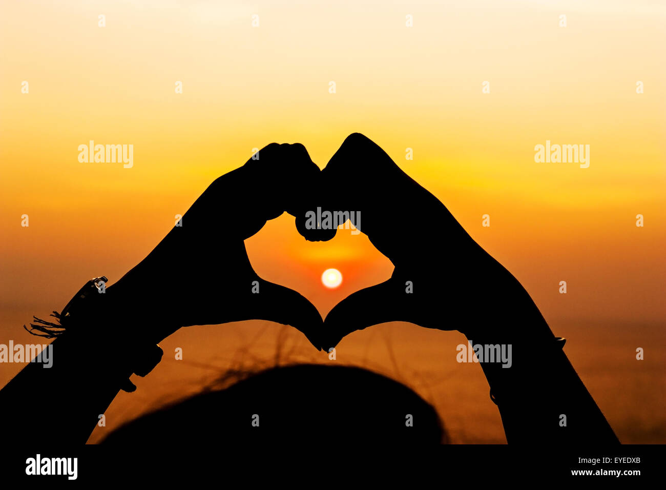 Silhouette, mano forma di cuore con i colori del tramonto Foto Stock