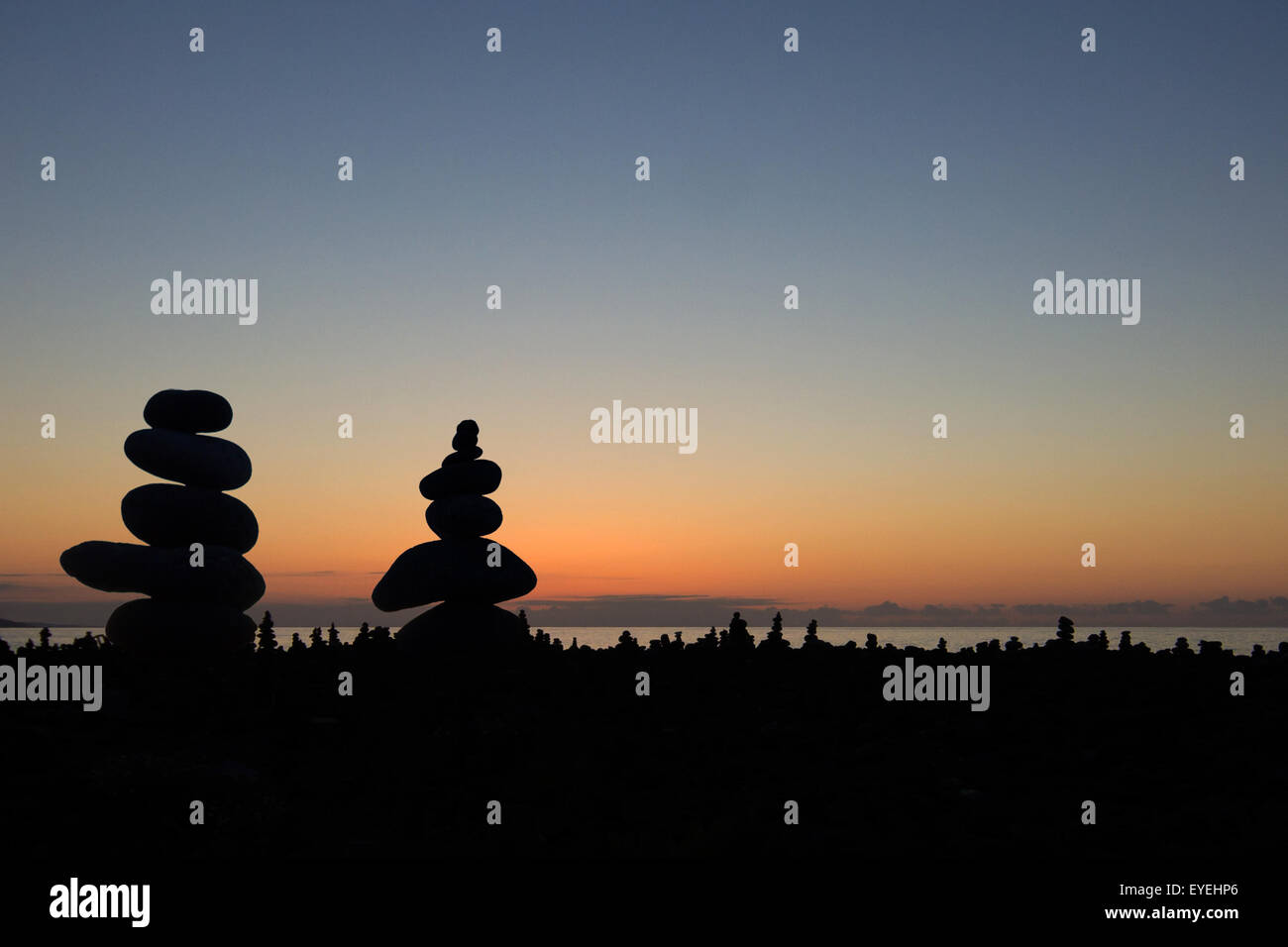 Pietre impilate / piramide di pietra in spiaggia con tramonto Foto Stock