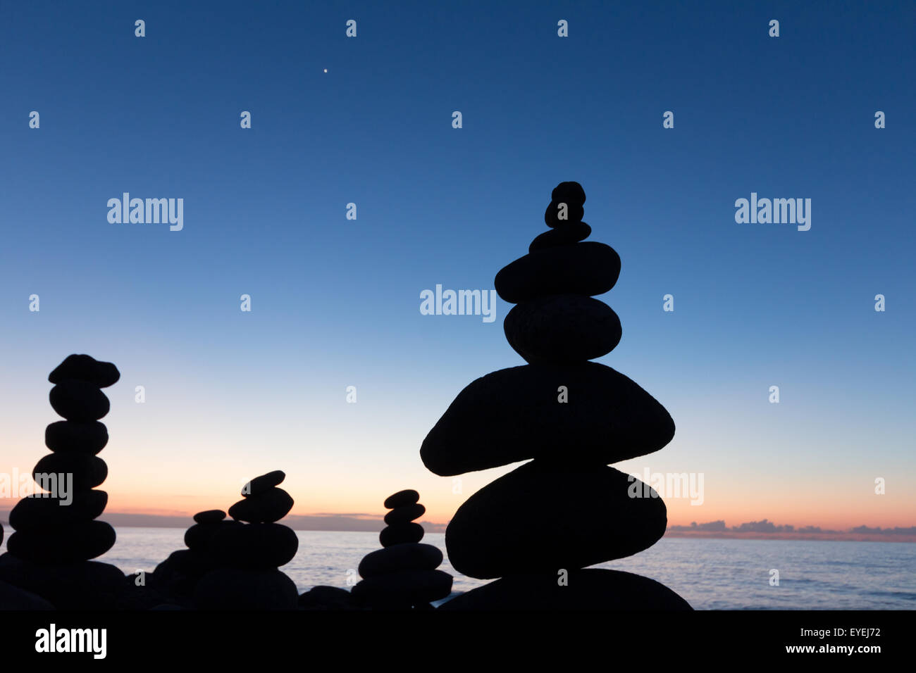 Pietre impilate / piramide di pietra in spiaggia con tramonto Foto Stock