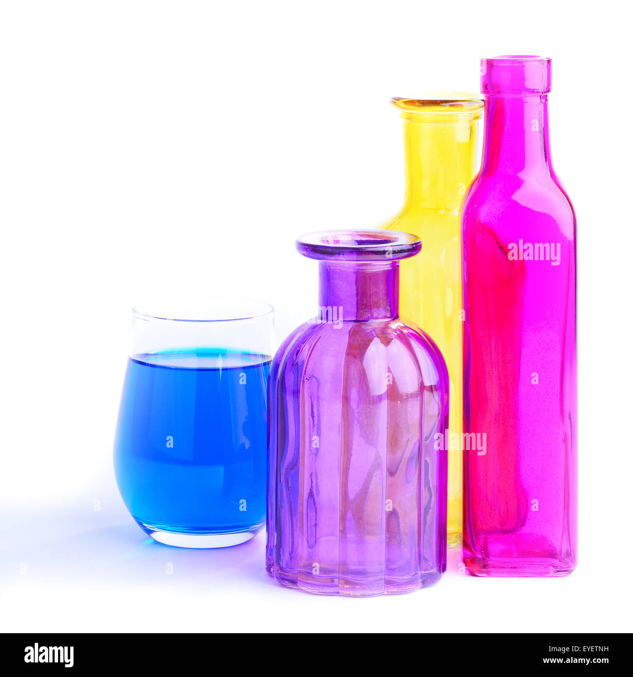 Tre bottiglie colorate e un vetro, isolati su sfondo bianco Foto Stock