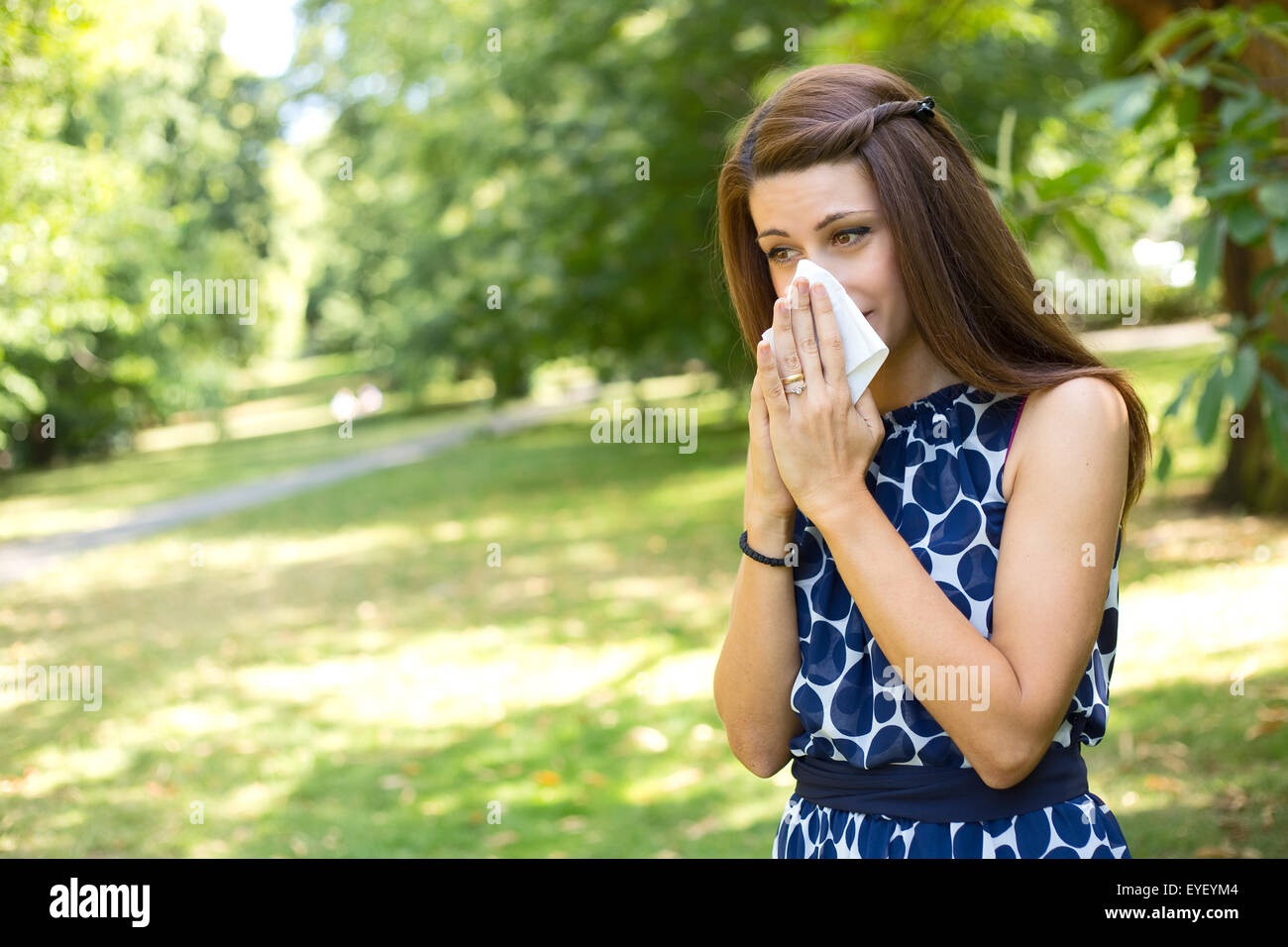 Giovane donna soffia il naso nel parco Foto Stock