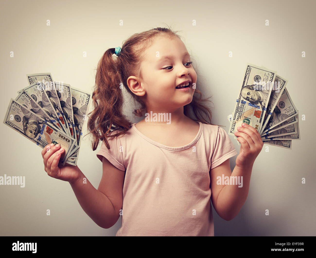 Capretto felice ragazza con dollari in contanti e guardando con sorriso. Vintage closeup ritratto Foto Stock