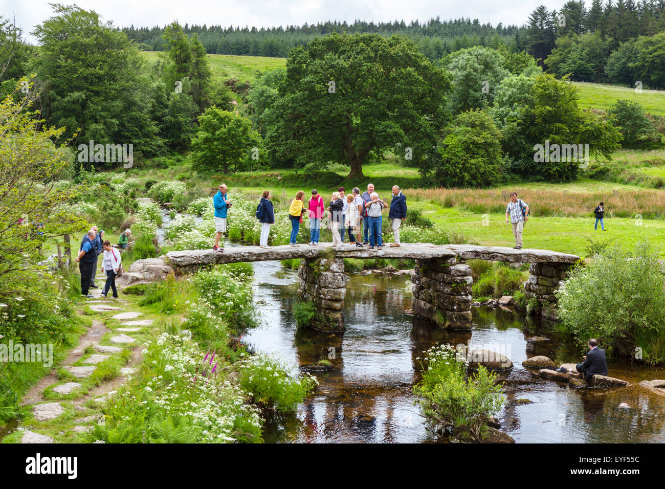 I turisti sulla storica del battaglio ponte sull'EST Dart River in Postbridge, Dartmoor Devon, Inghilterra, Regno Unito Foto Stock
