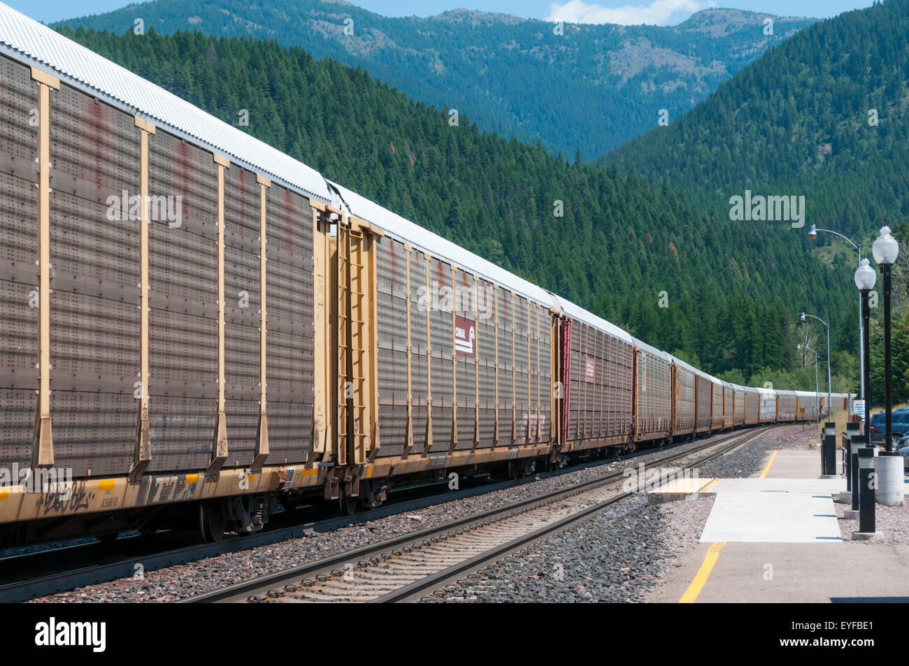 Un lungo American treno merci passa attraverso la piccola stazione di West Glacier in Montana. Foto Stock