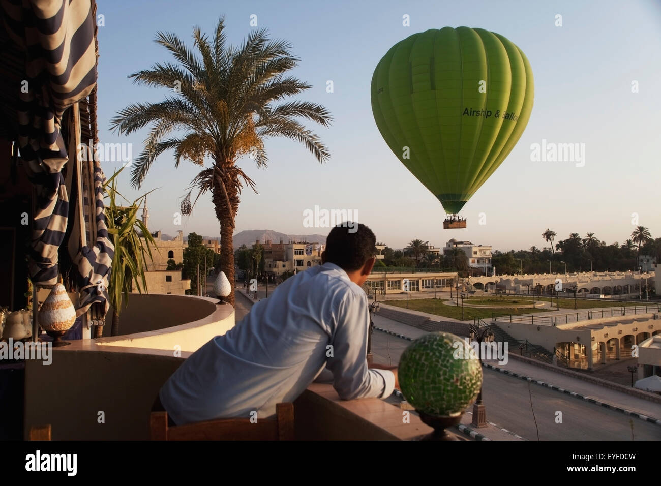 Hotel lavoratore guardando la mongolfiera da hotel balcony; Cisgiordania Luxor Egitto superiore Foto Stock