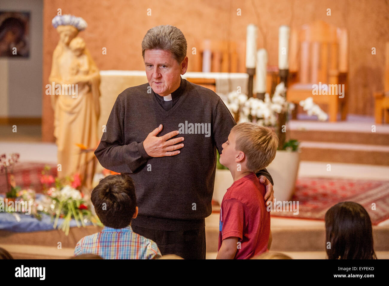 All'incoronazione di Maria in una Laguna Niguel, CA, chiesa cattolica, monsignor risposte le domande dei bambini sulla cerimonia. Può devozione alla Beata Vergine Maria sono una Cattolica Romana tradizionale rituale venerandola come "la regina di maggio." Nota statua in background. Foto Stock