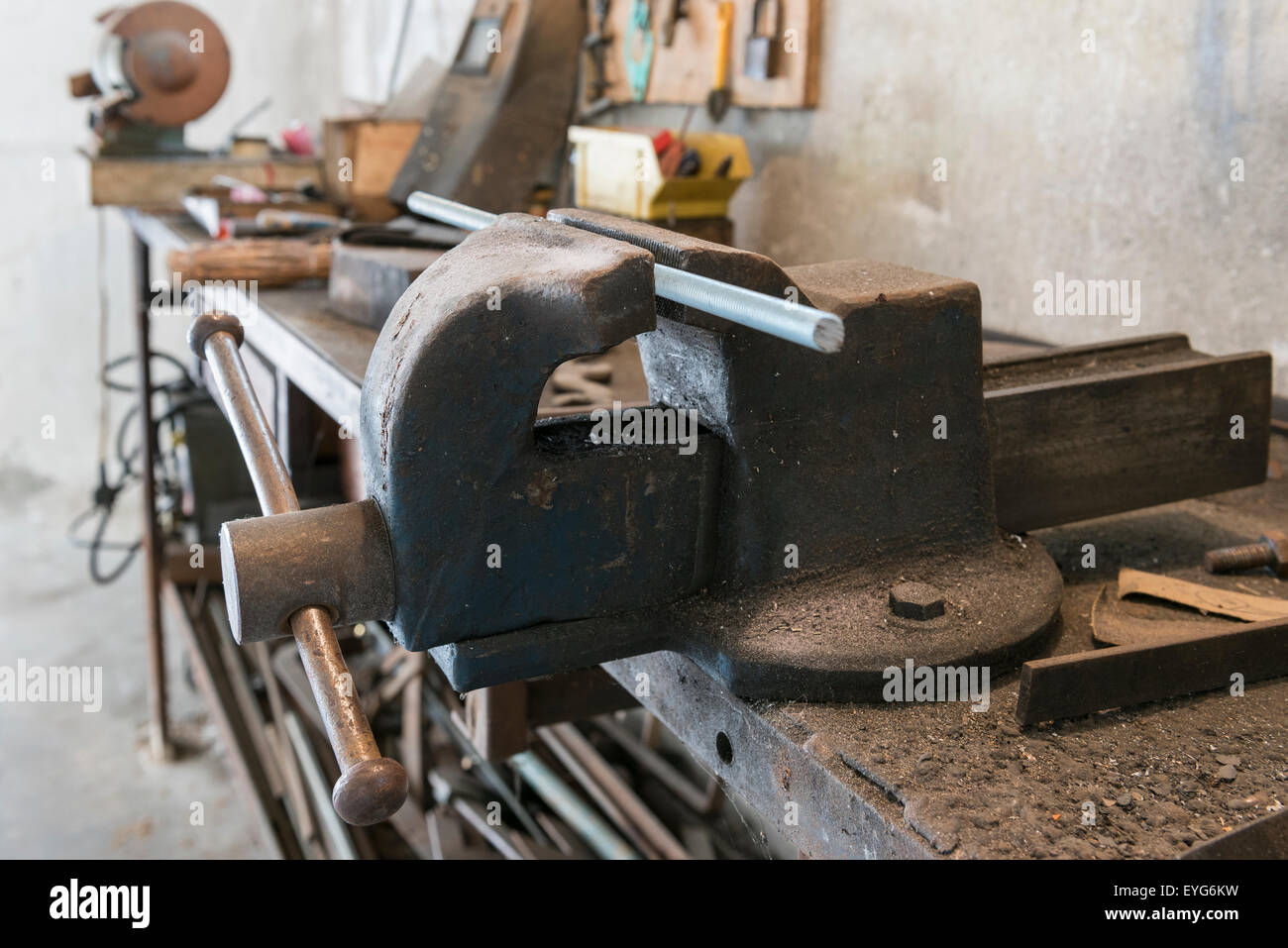 Vecchia morsa da banco con barra filettata e vecchi strumenti di lavoro nel garage di casa Foto Stock