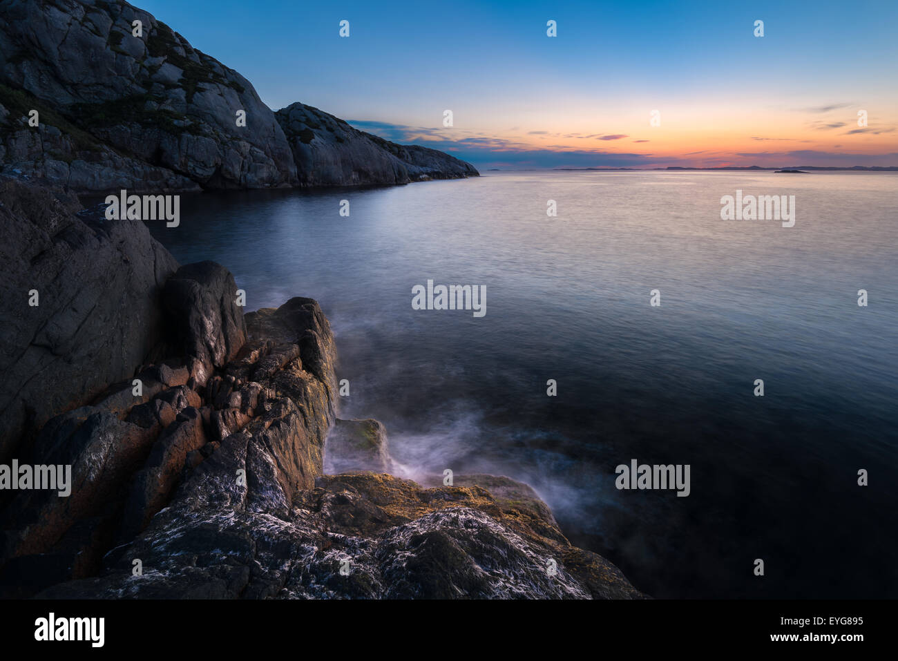 Forme d'onda colpendo la riva durante il tramonto a la westcoast della Norvegia Foto Stock