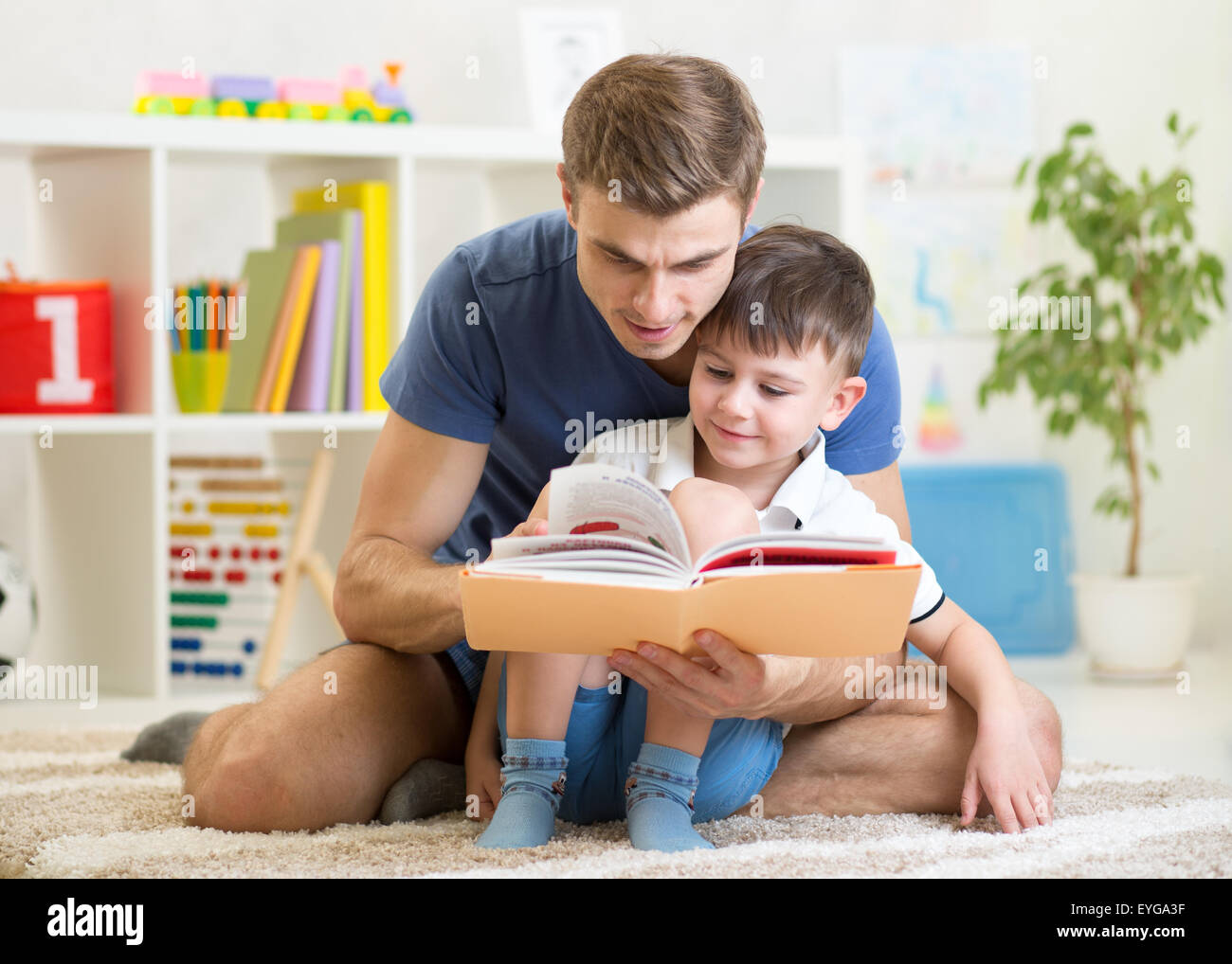 Kid boy e padre di leggere un libro in ambienti interni Foto Stock