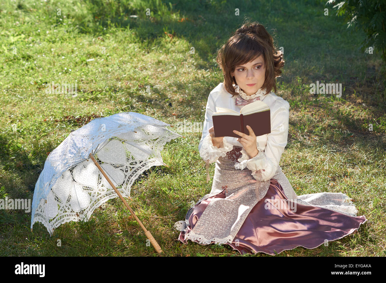 Ragazza in stile retrò vestito pensa al romanzo che essa legge all'aperto Foto Stock