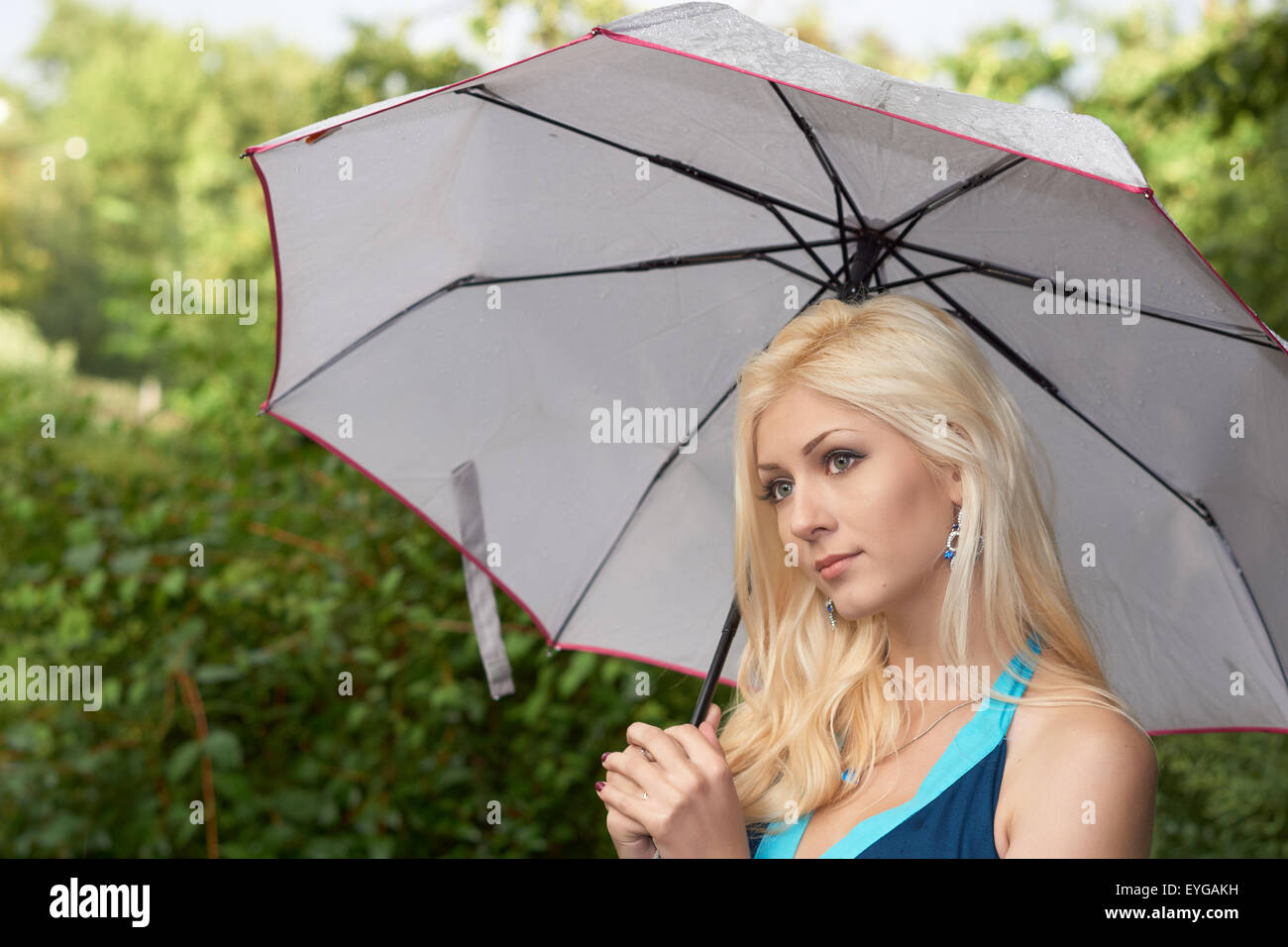 Bella ragazza bionda con ombrello in estate park dopo la pioggia Foto Stock
