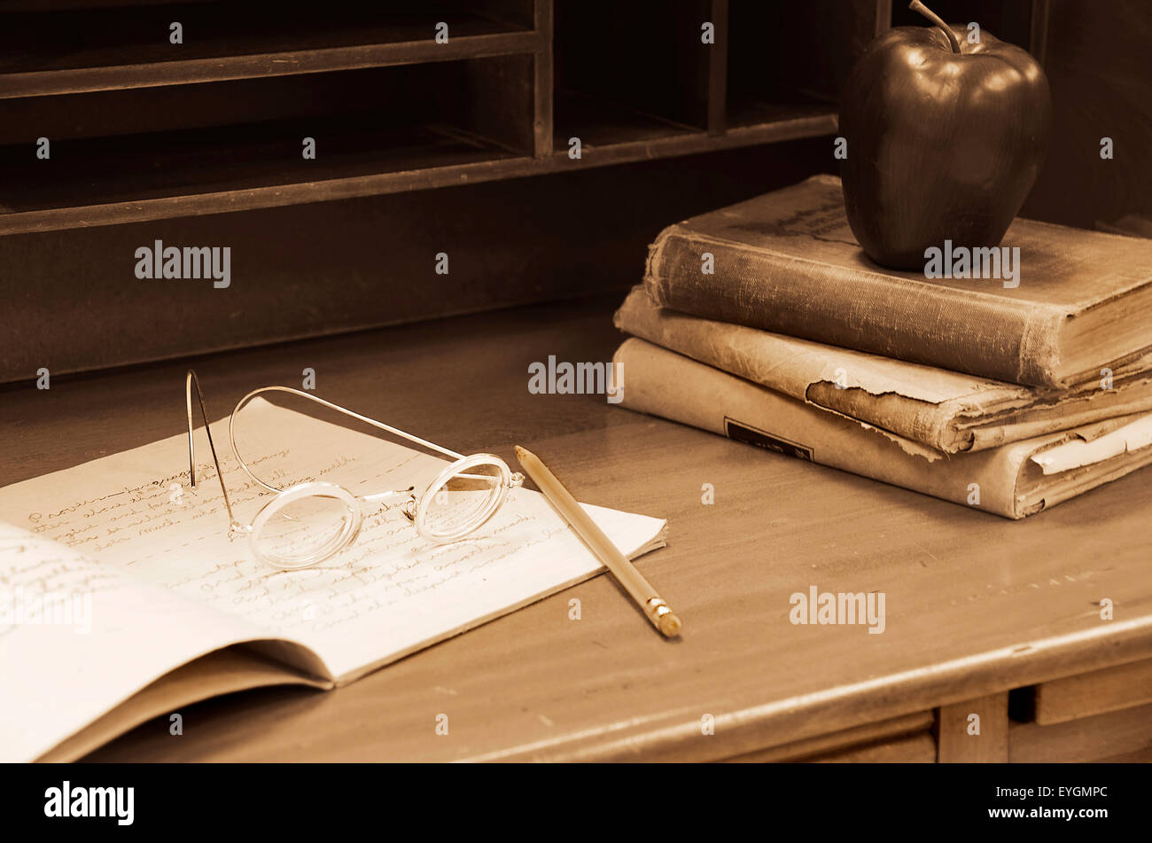 Un vecchio stile degli occhiali con libri, apple,matita e portatile su un antico maestro's desk. Foto Stock