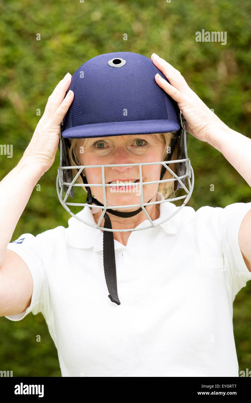 Ritratto di una donna anziana cricketer indossando un batswoman il casco di sicurezza Foto Stock