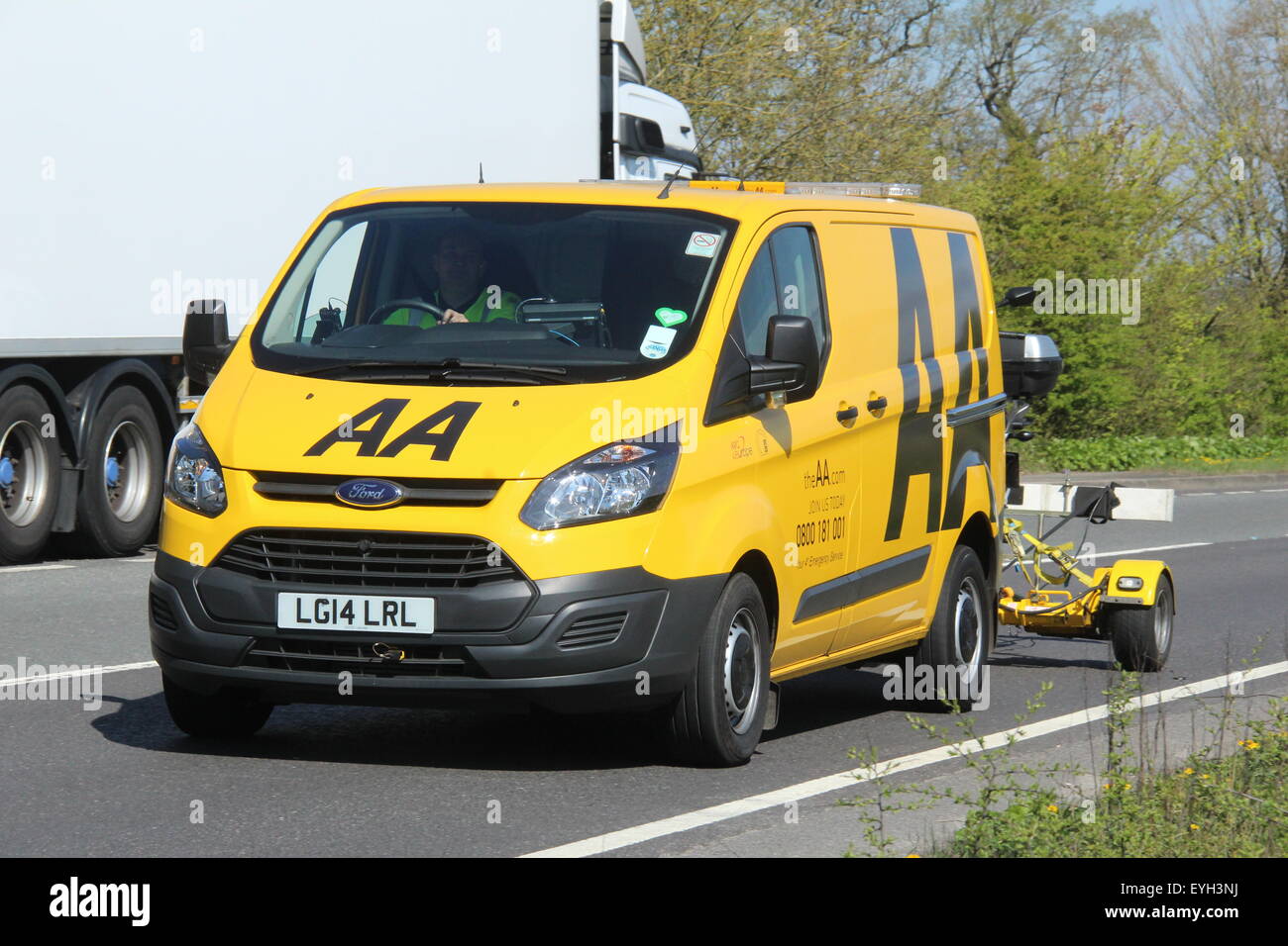 Un 2014 AA RIPARTIZIONE RESCUE GIALLO VAN guidando lungo la principale strada con un rimorchio che trasportano una motocicletta Foto Stock