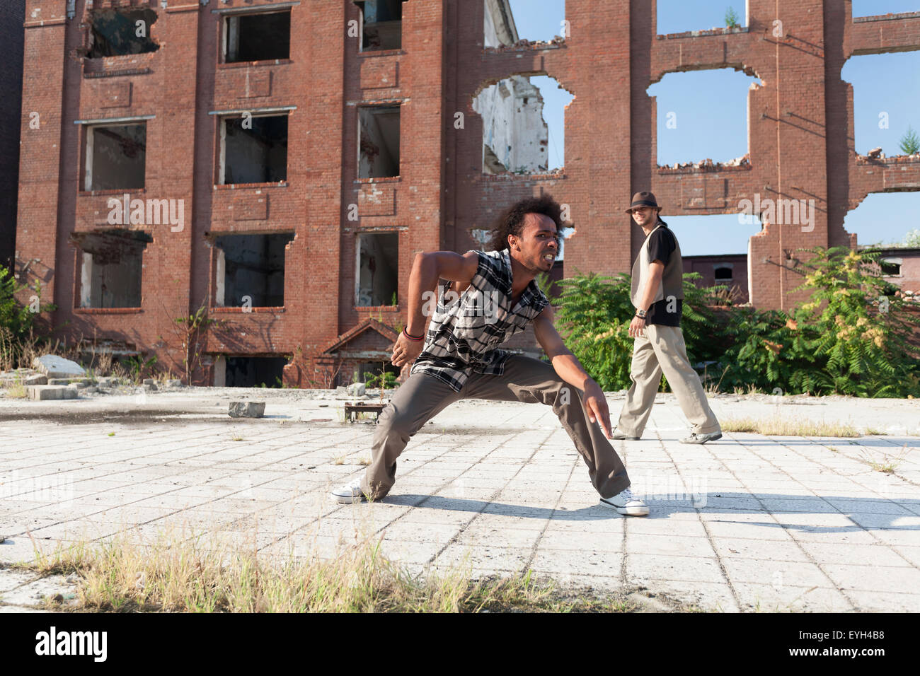 Due giovane africano americano uomini street dancing in una piazza urbana di eseguire un energico routine di hip hop si muove retroilluminati da una b Foto Stock