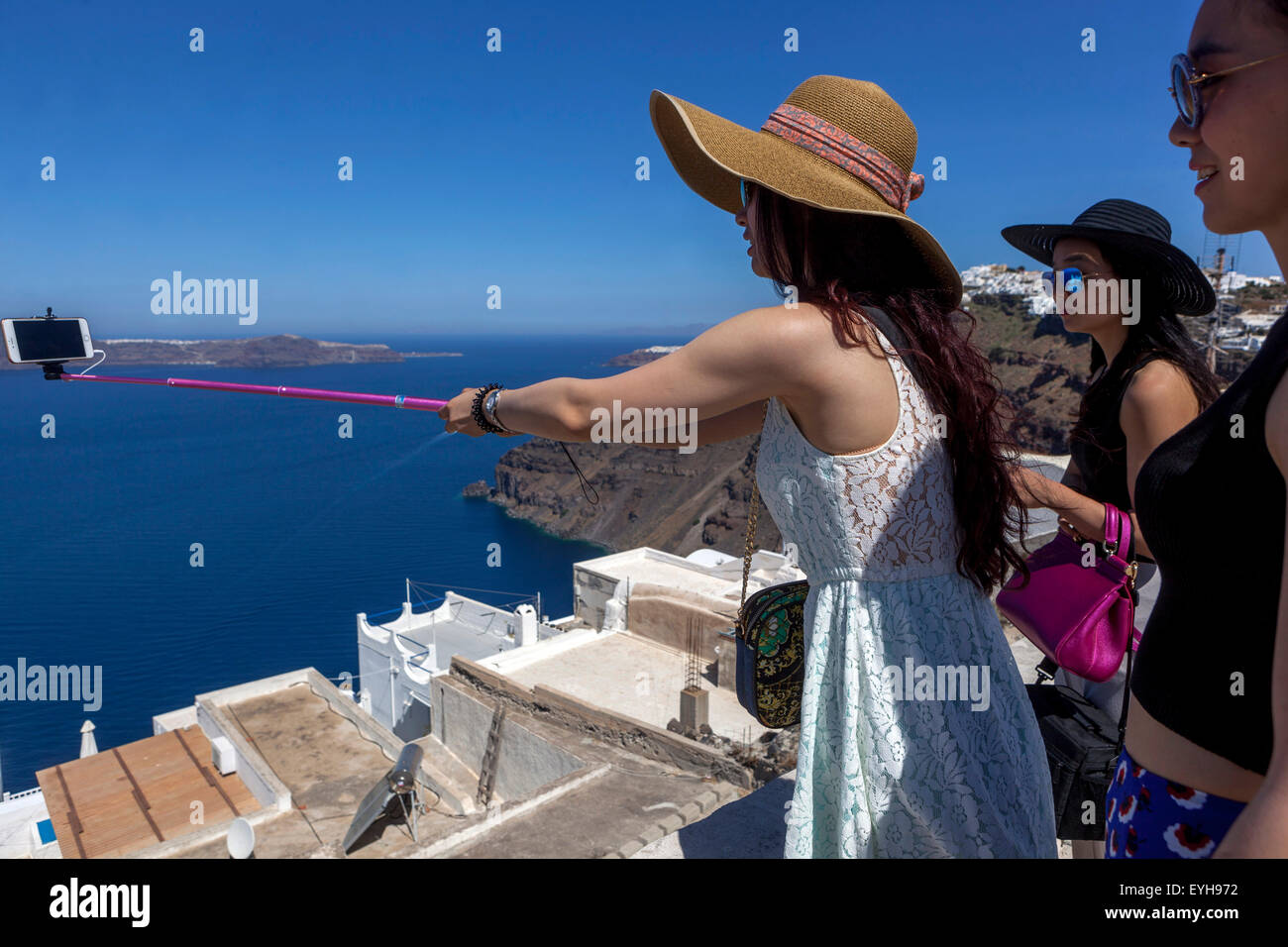 Persone, Asian turistica prendendo un selfie nel villaggio di Firostefani, sulla caldera e sul mare. Santorini, isole greche, Grecia Europa Foto Stock