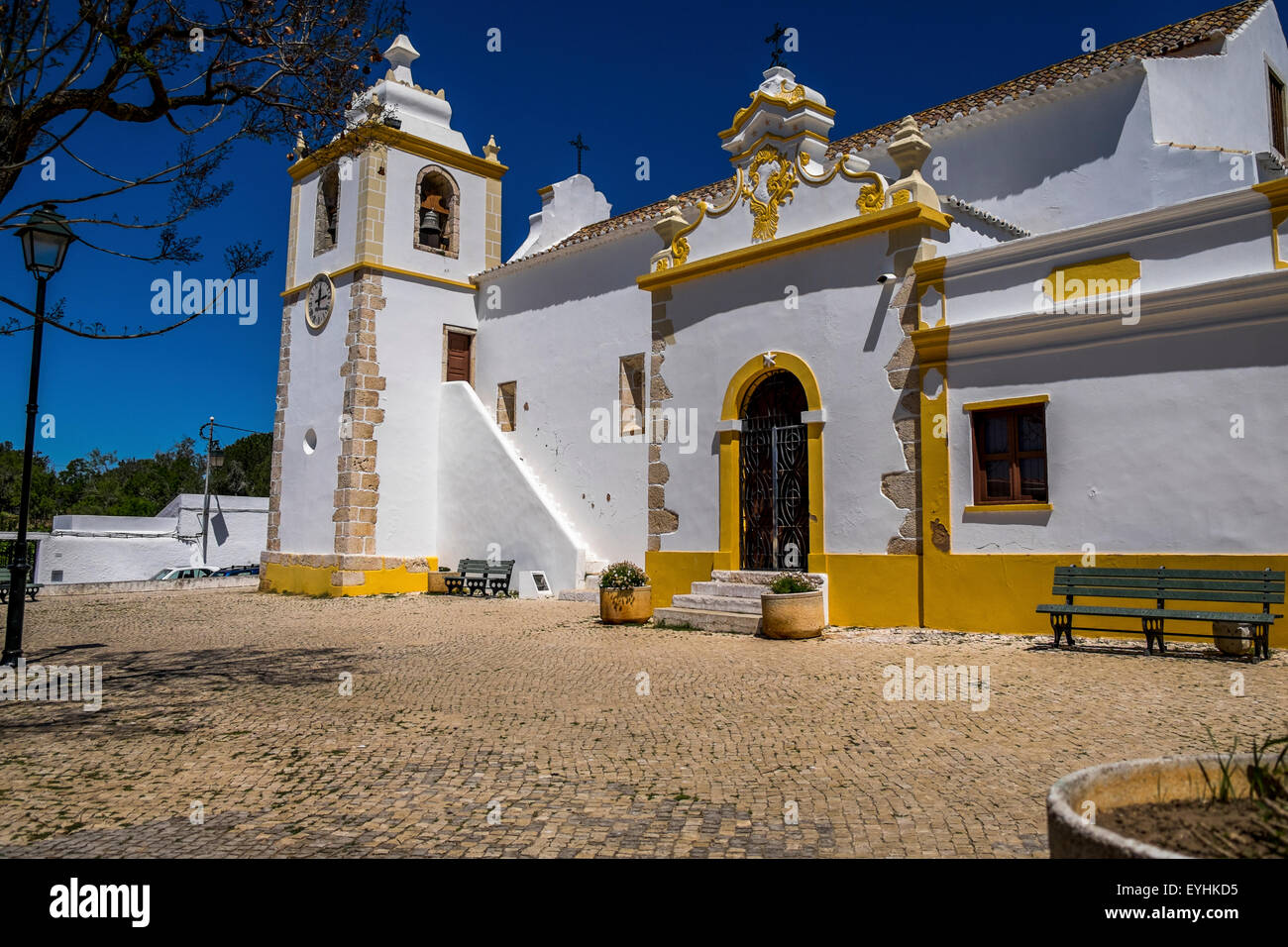Chiesa portoghese dipinto di bianco e giallo con un acciottolato percorso di ingresso. Foto Stock