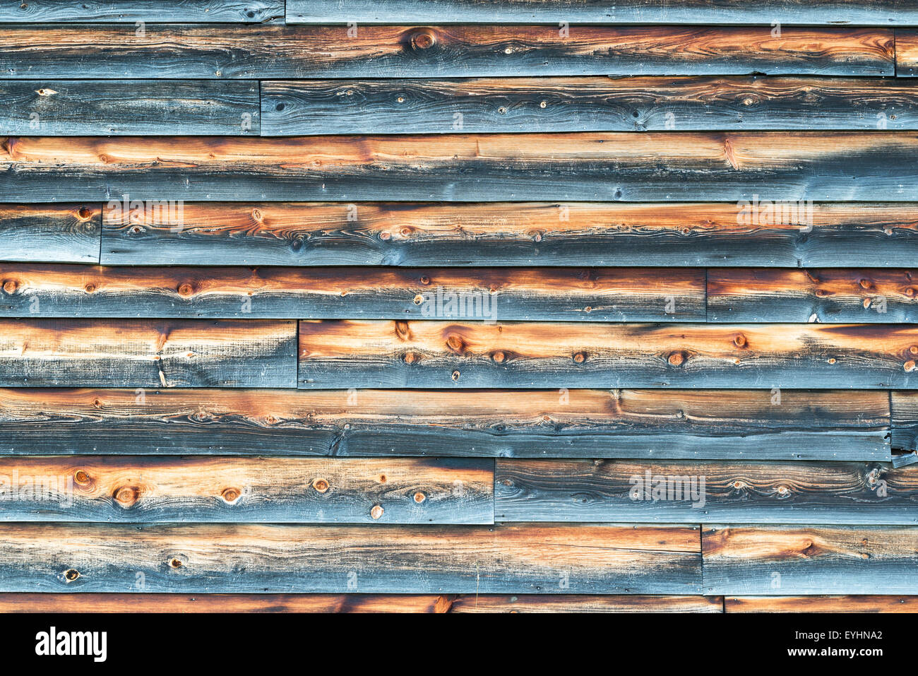 Weathered muro del granaio di sovrapposti grigio e marrone del legno schierata in cattive condizioni. Foto Stock