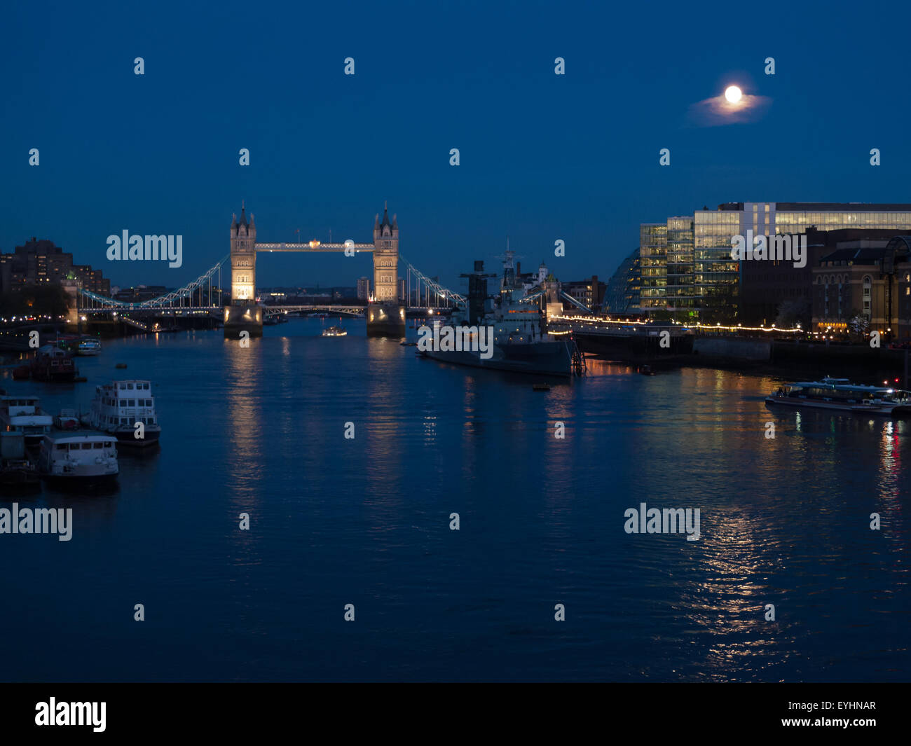 Londra, Inghilterra. Lungo il Tamigi di notte, il Tower Bridge e la luna. Foto Stock