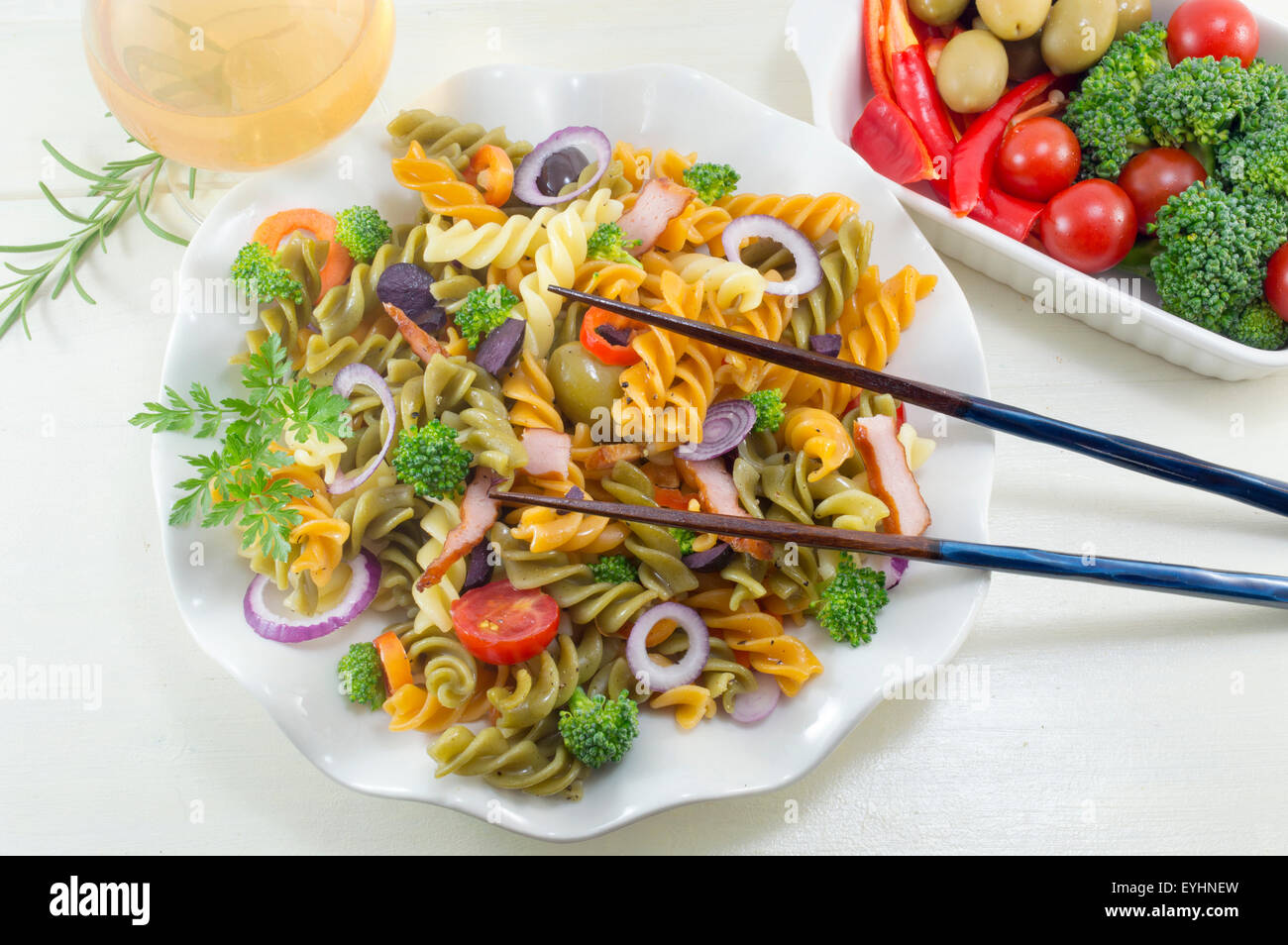 Pasta maccheroni pasto cucinato con verdure con verdure fresche servita con bacchette e un bicchiere di vino Foto Stock